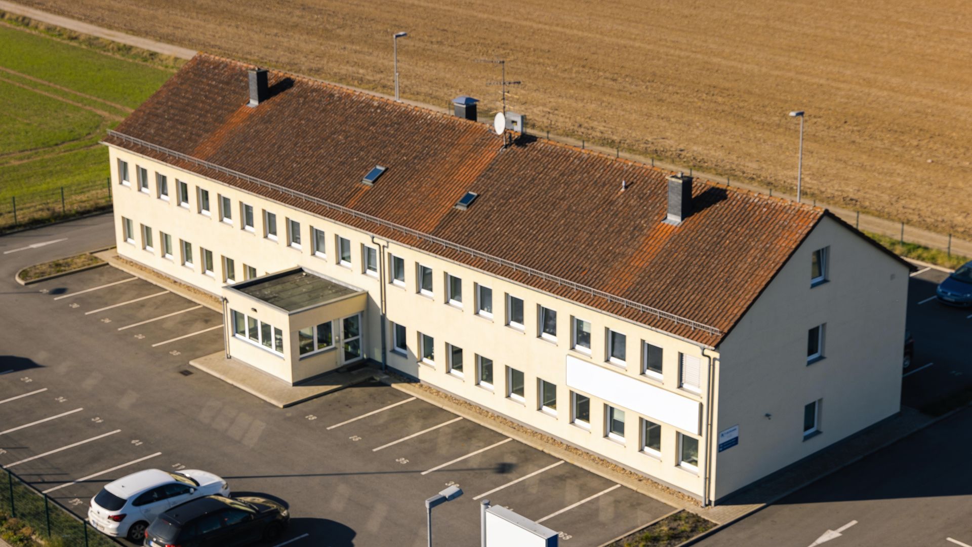 Gewerbegebäude mit Steildach und Putzfassade, Schrägluftbild (KI-erzeugter Platzhalter)